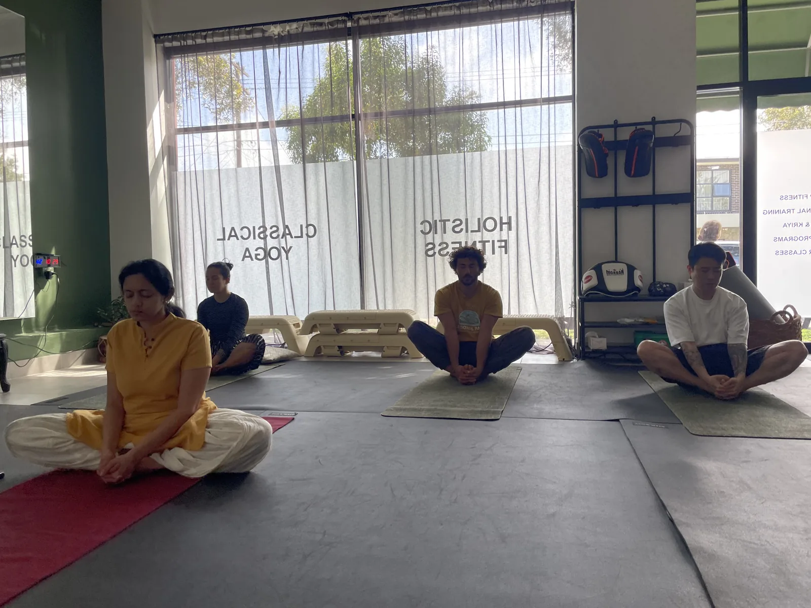 Group yoga class seated on mats together at the Adiyoga studio in Earlwood