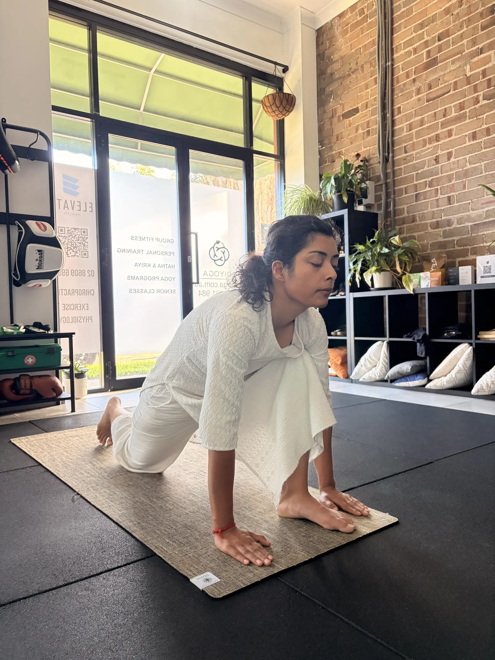 Yoga student kneeling in a grounded pose on a mat at Adiyoga studio in Earlwood